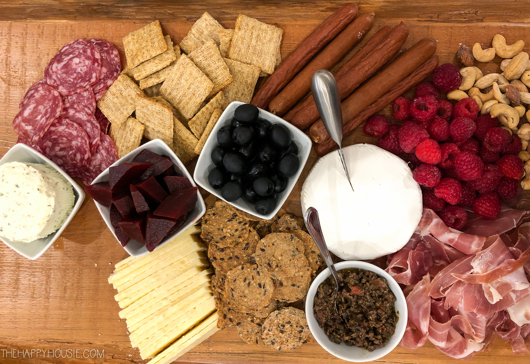 The charcuterie board with crackers and berries on it.