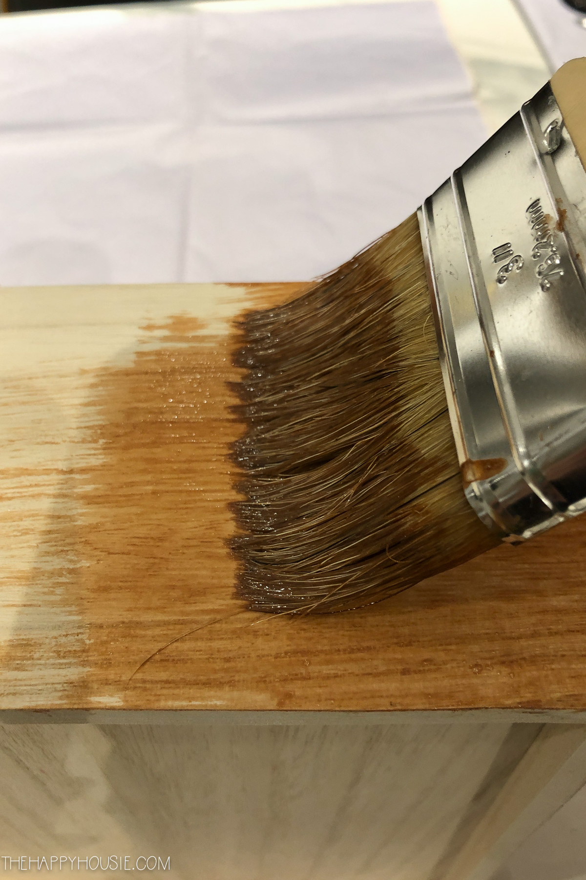 Using a paint brush staining the wood.