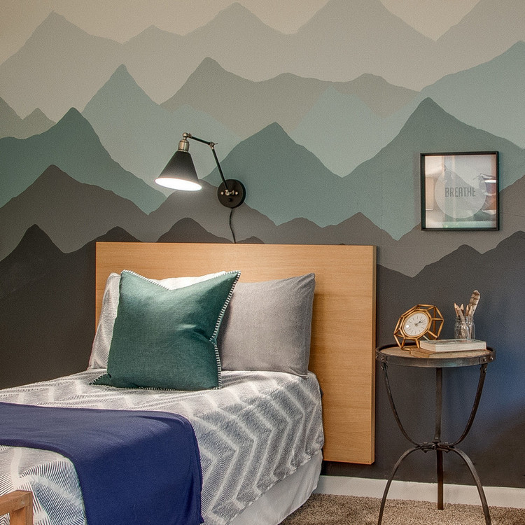 A mural wall behind a bed in a mountain theme.