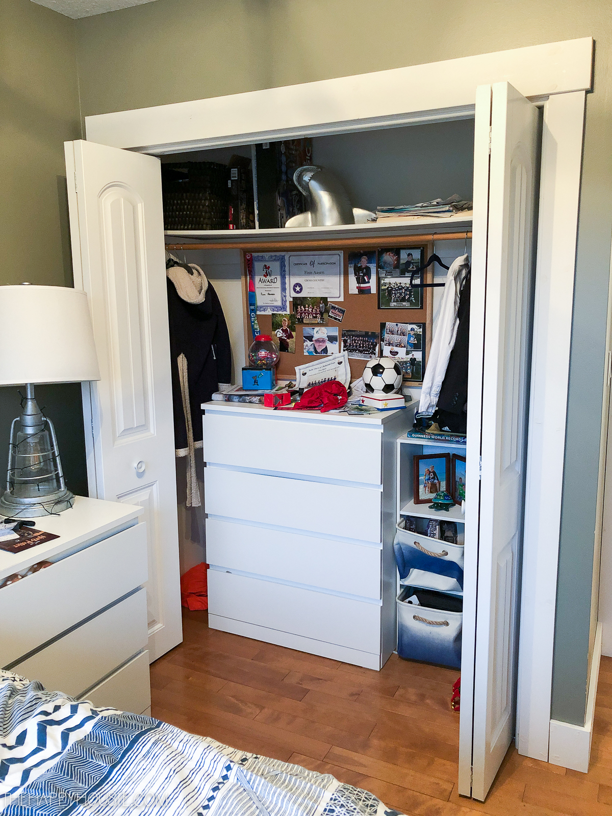The closet doors are open revealing a chest of drawers and sports items.