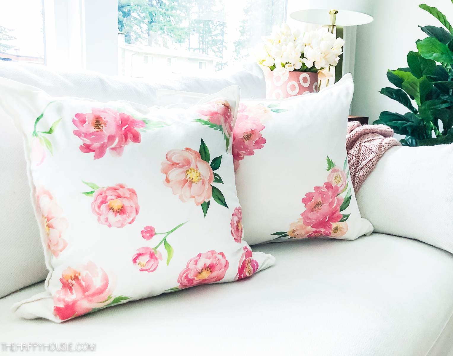 Two floral pillows on a white couch.