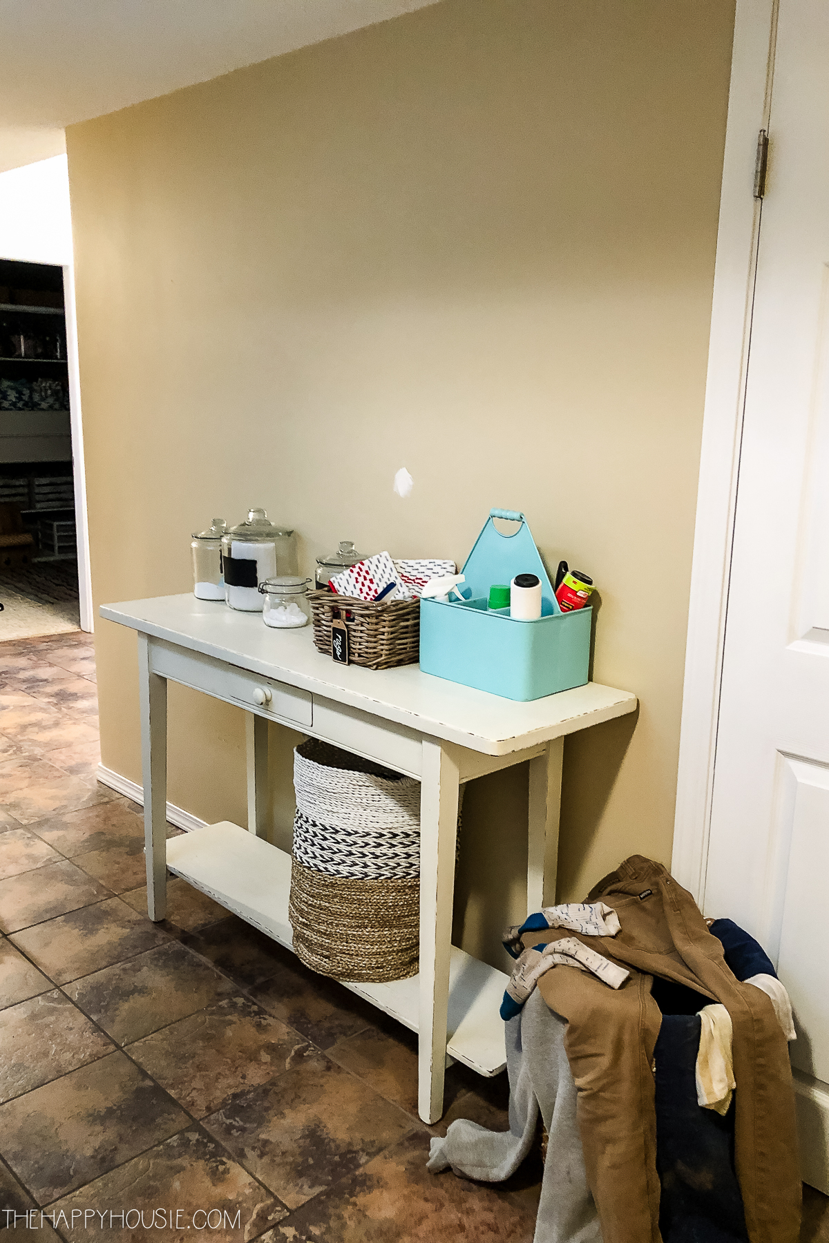 A small hallway table with laundry items on it.