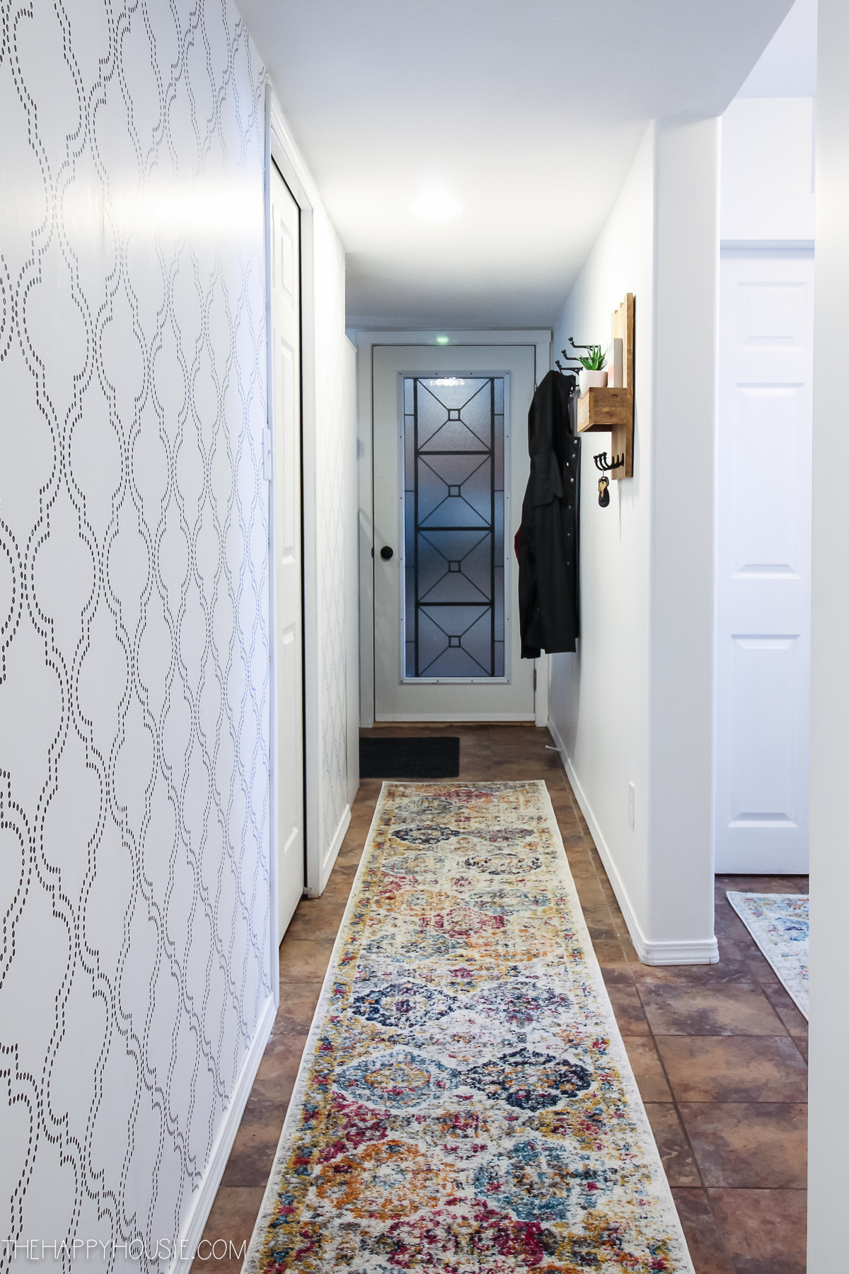 A long rug runner in multi colours lines the hallway.