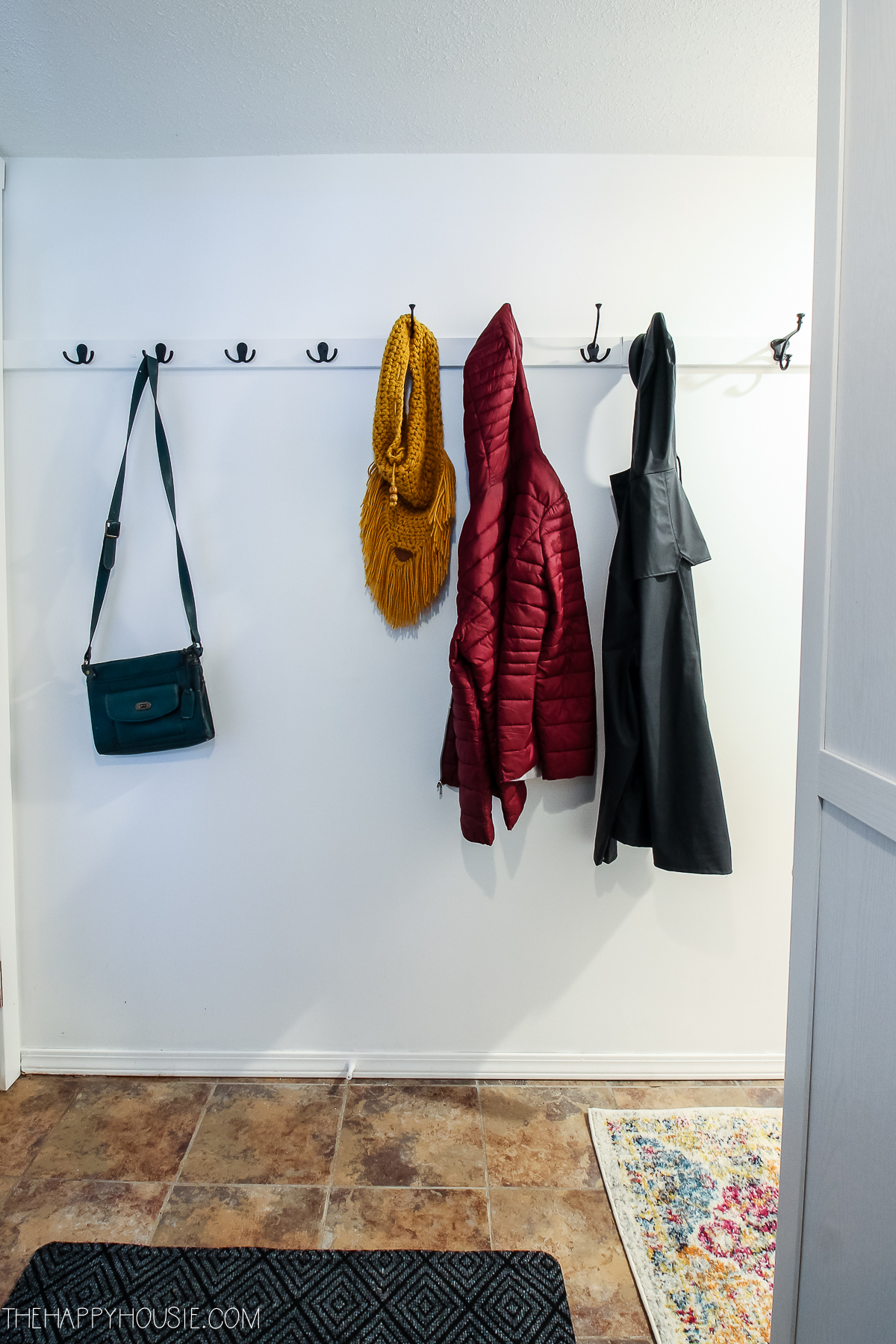 Coats and purses are on the hooks in the hallway.