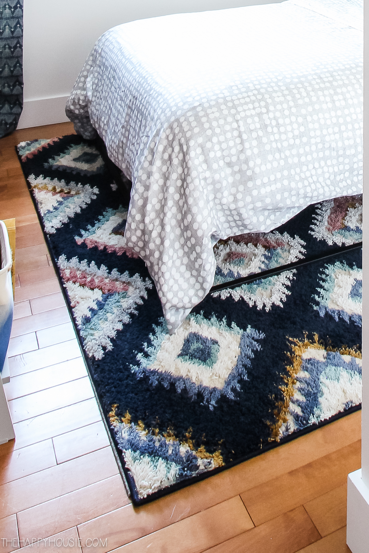A multi coloured area rug is underneath the bed.