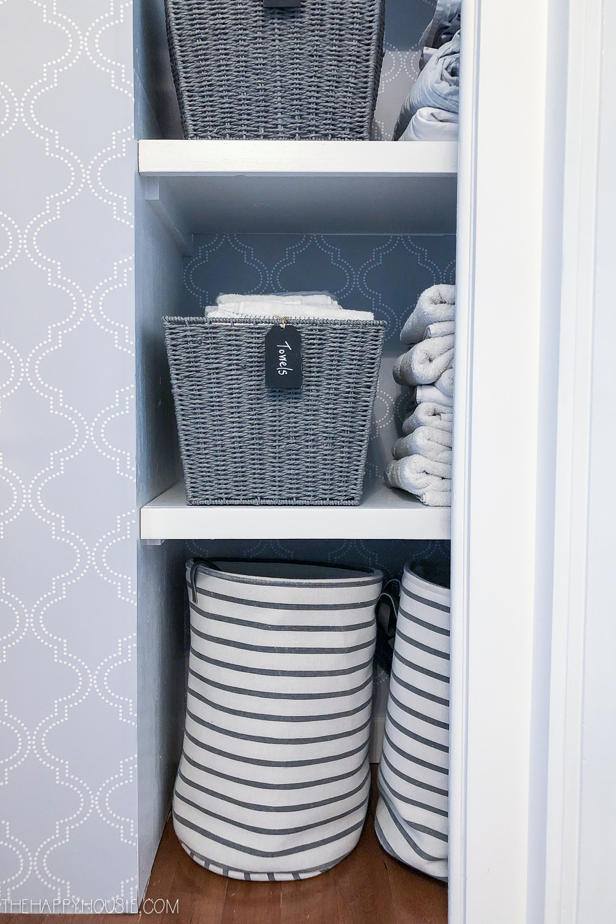 Striped baskets on the bottom of the linen shelf.