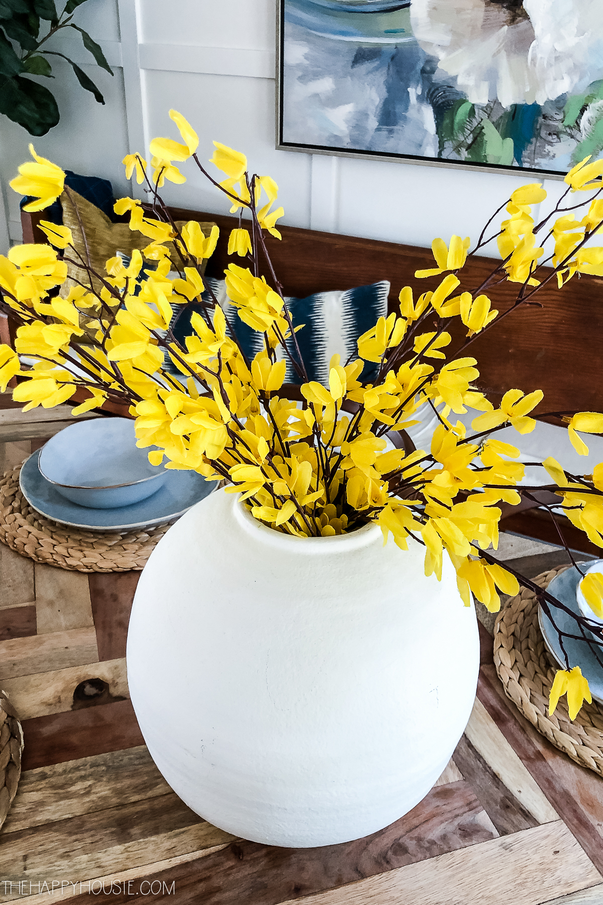 Yellow forsythia blooms in the white vase.