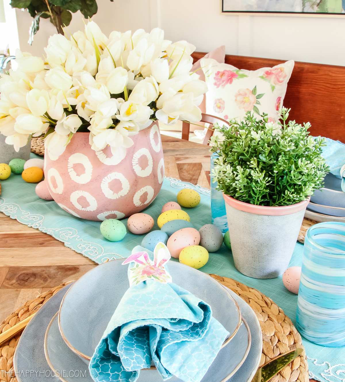 There are scattered Easter eggs in pink, blue and yellow on the table.