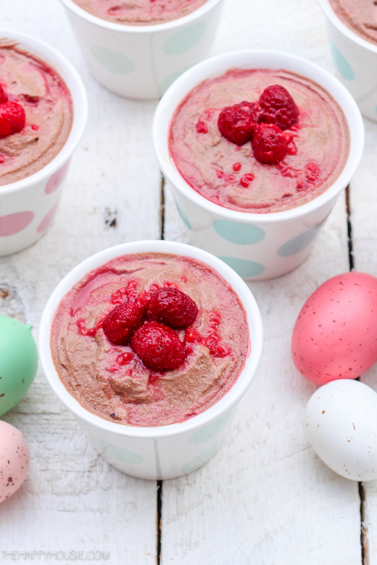 Easter eggs are scattered in between the mousse in cups.