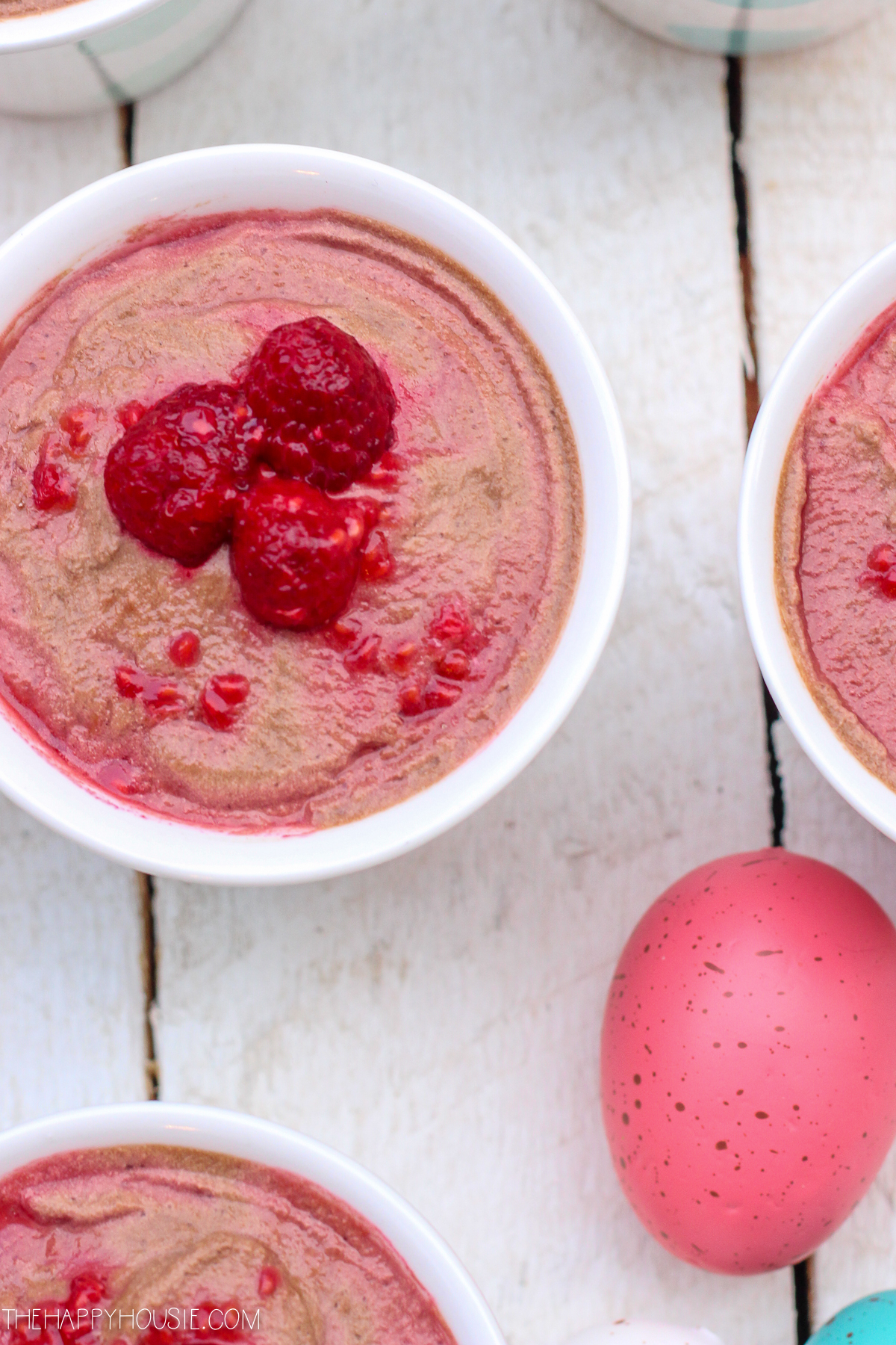 The pinkish dessert in a cup with a dyed pink egg beside it.
