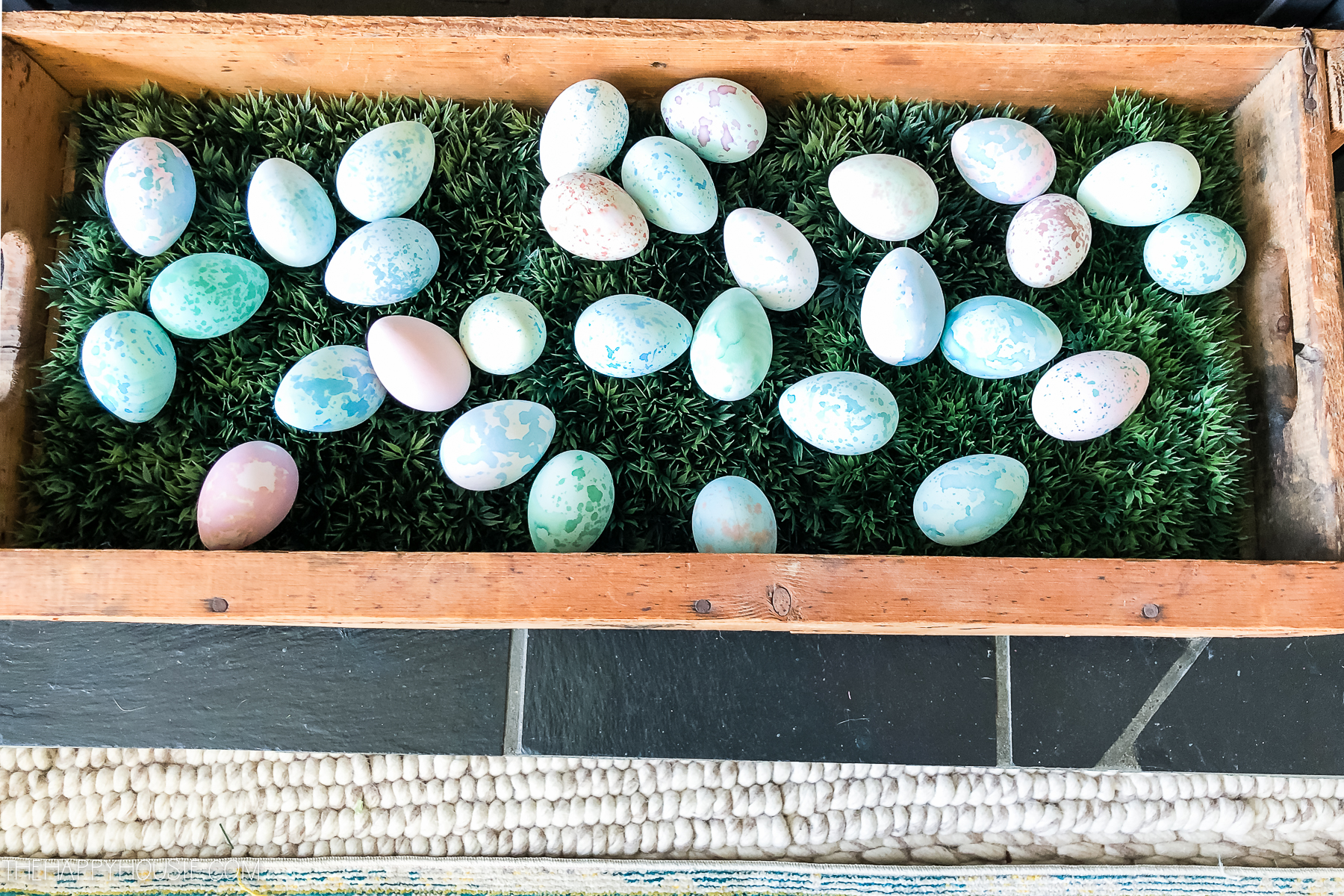 A wooden crate filled with coloured Easter eggs.