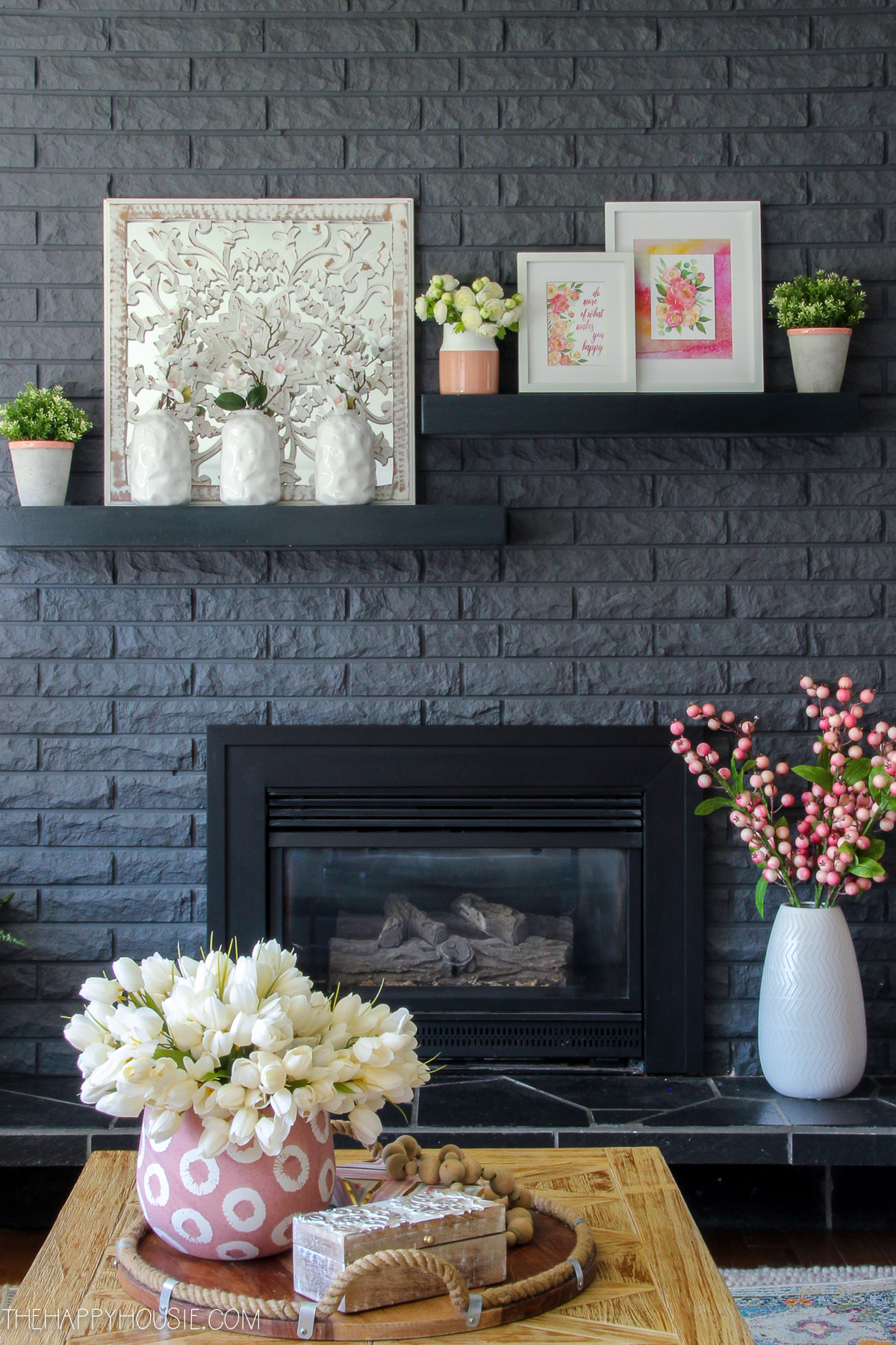 White vases filled with flowers ad shelves above the fireplace.