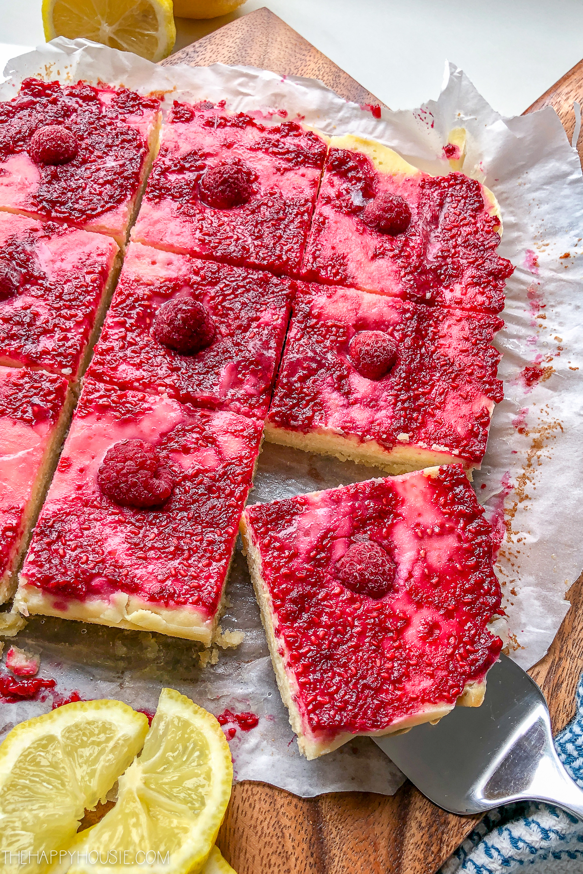 The raspberry bars on a plate with a fork in one.