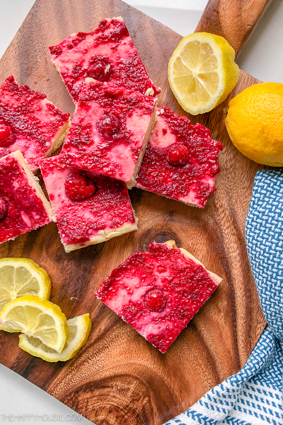 Raspberry bars and cut lemons on the wooden cutting board.