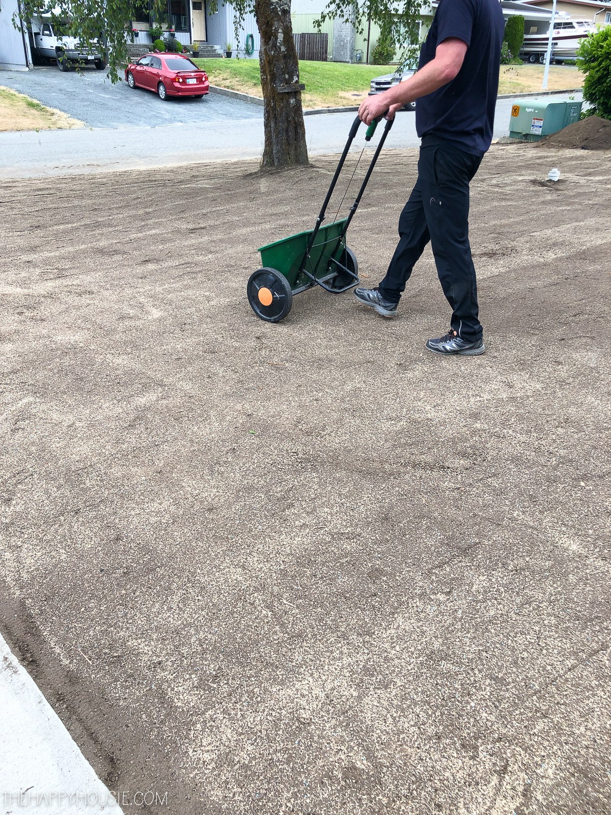 A man using a seed machine on the ground.