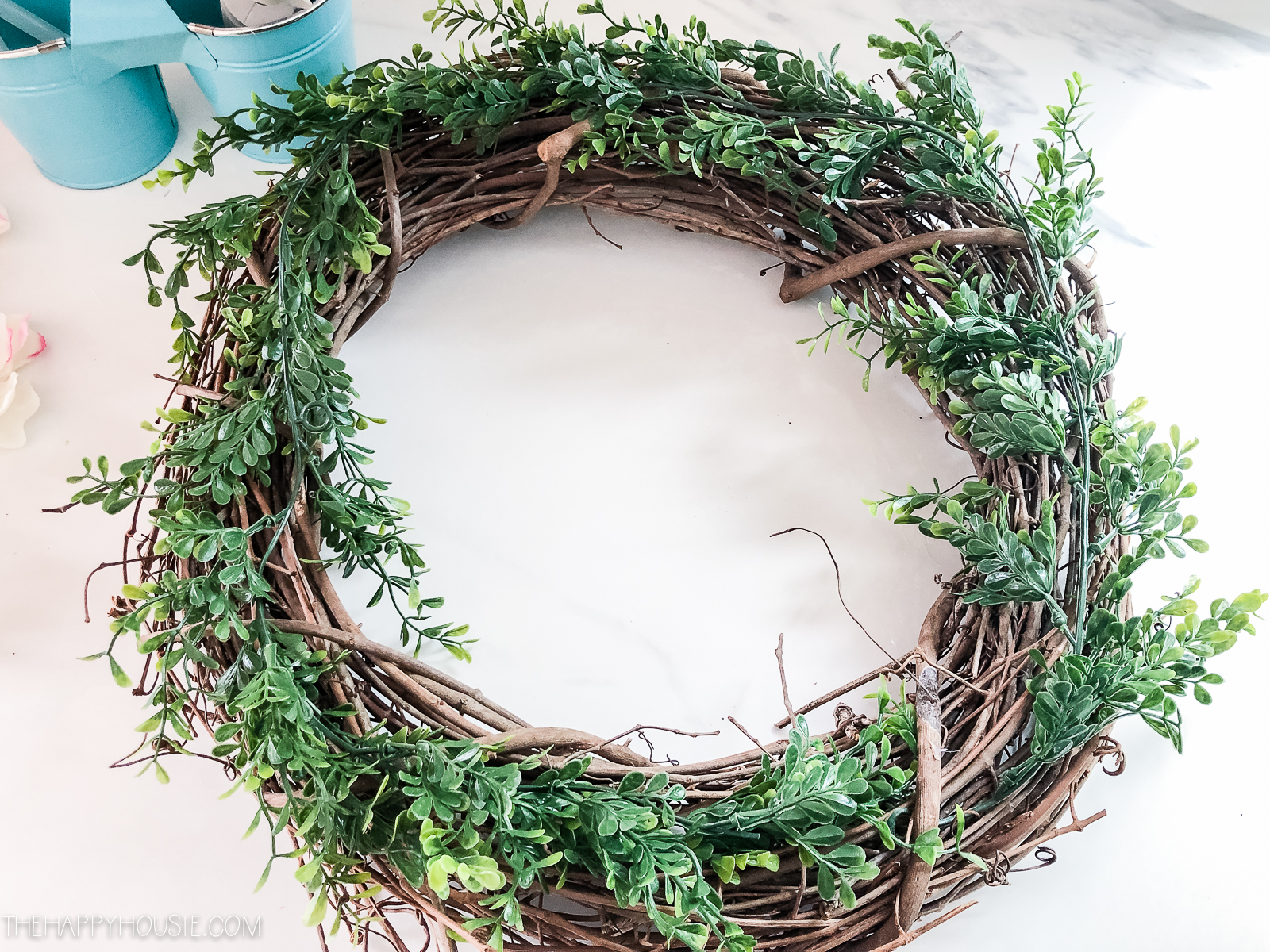 The wreath with greenery on it on the table.