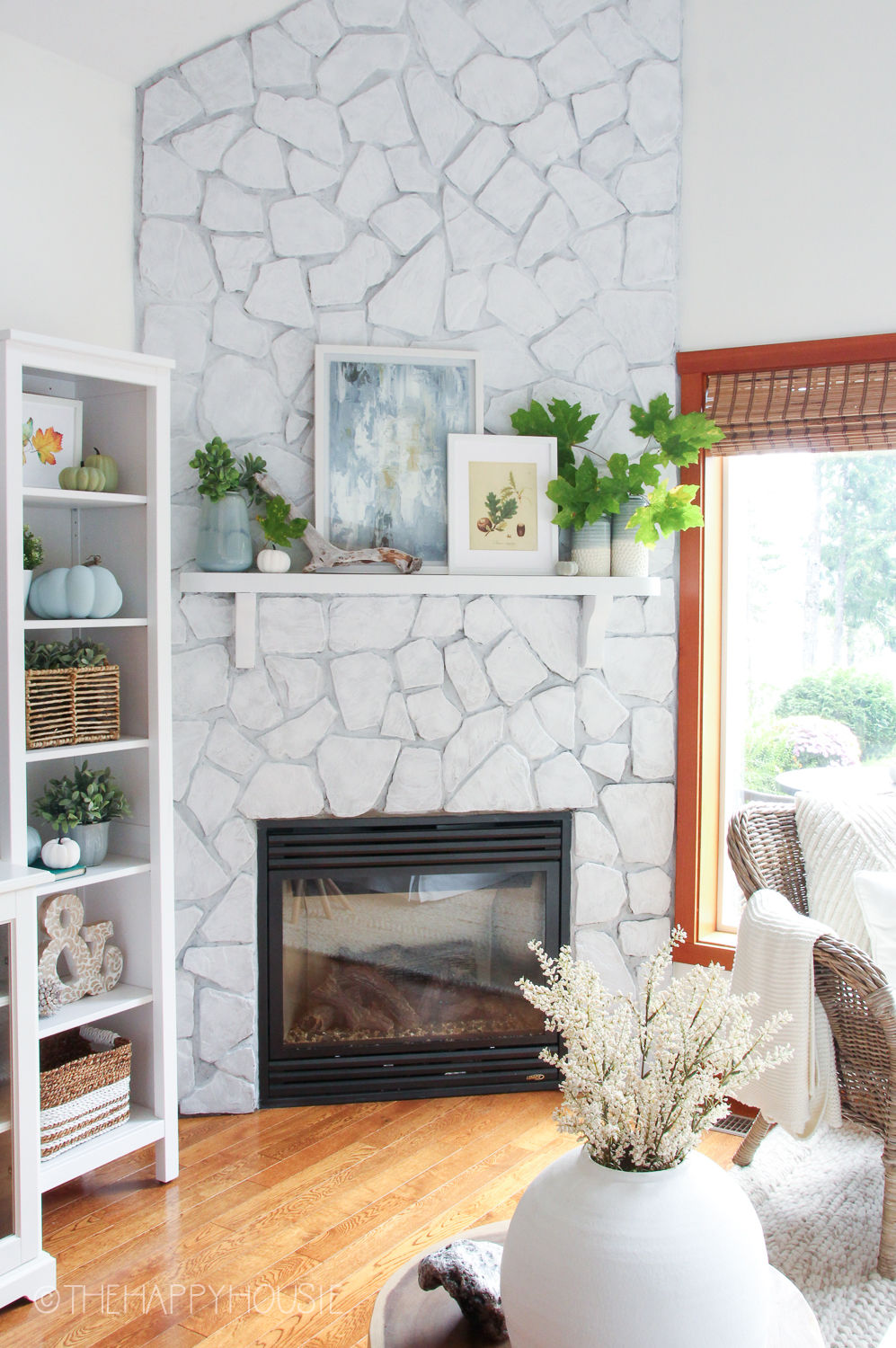 Open shelves with fall decor are beside the fireplace mantel.