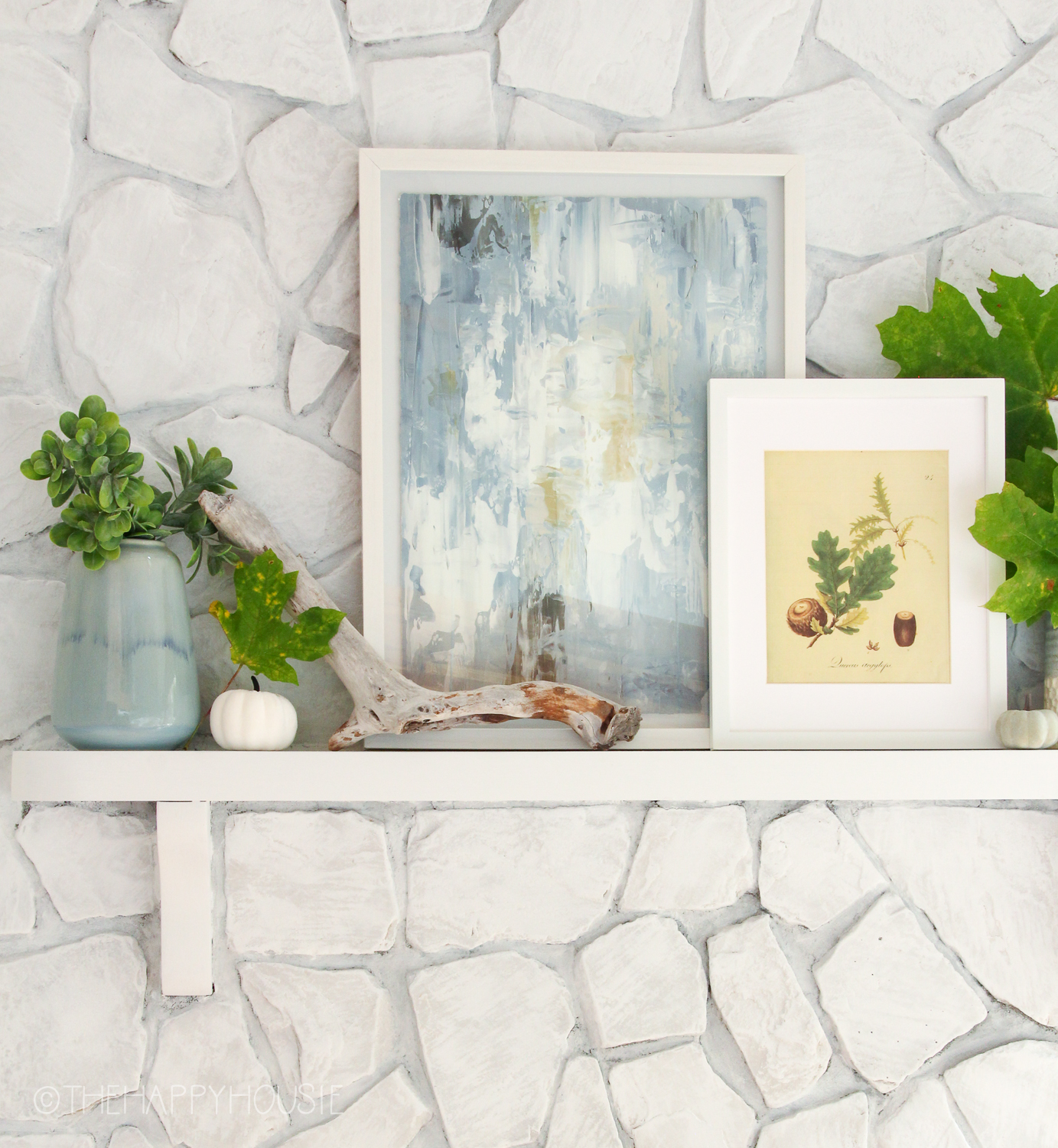 A watercolour framed print is on the mantel in shades of blue and grey.