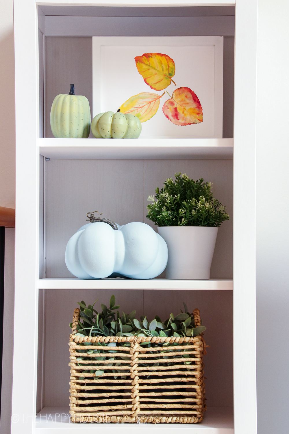 Up close picture of the leaf print in yellow and red, and the pumpkins on the shelf.
