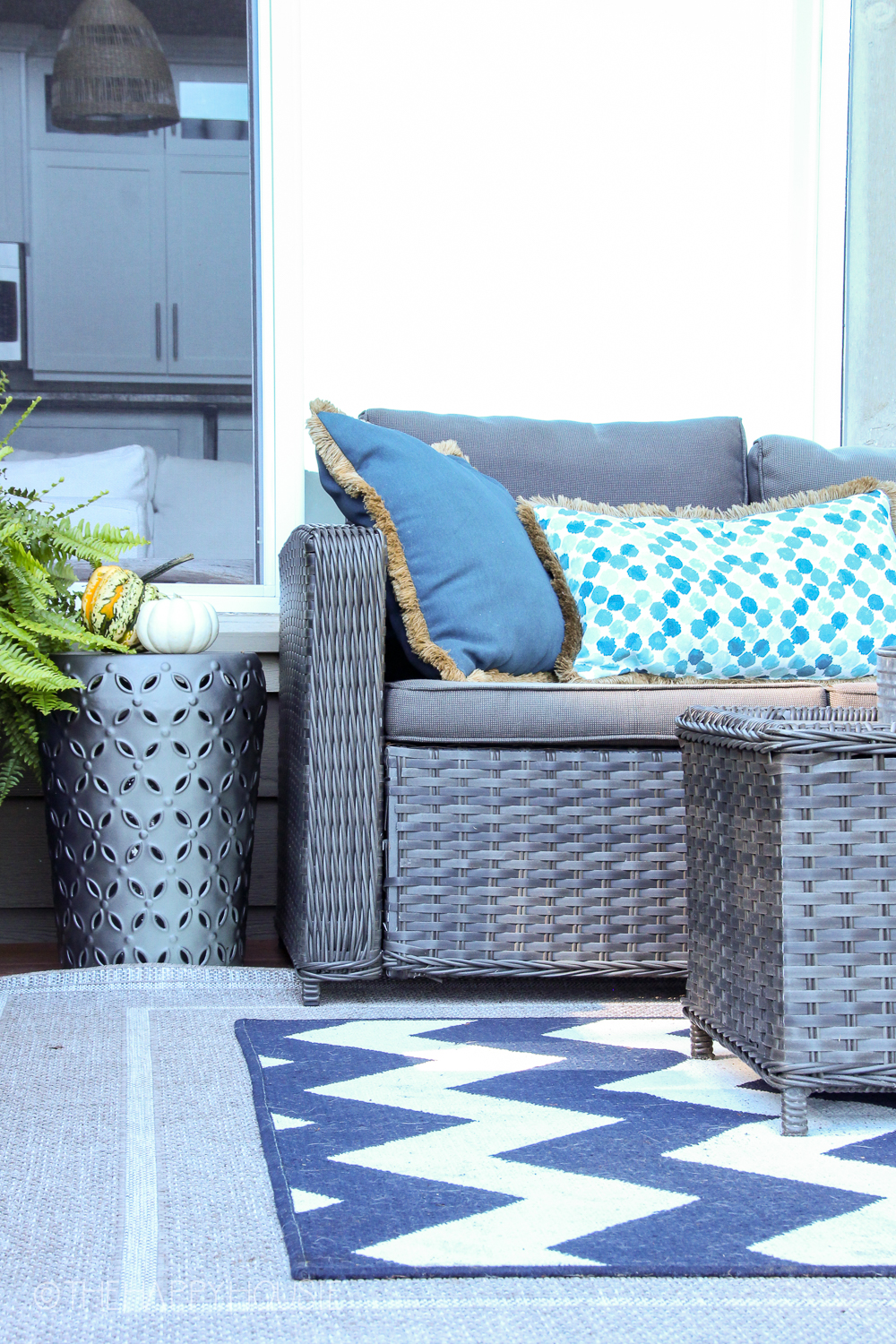 Beautiful blue and white throw pillows are on the outdoor couch.