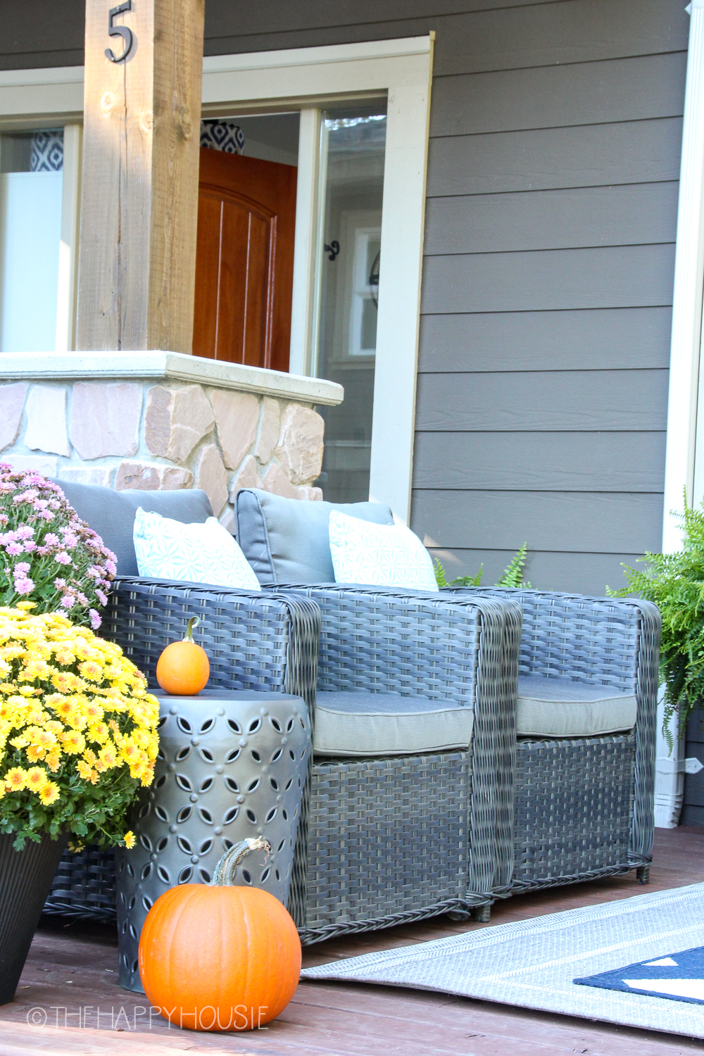 There are two outdoor wicker chairs with cushions on the deck.