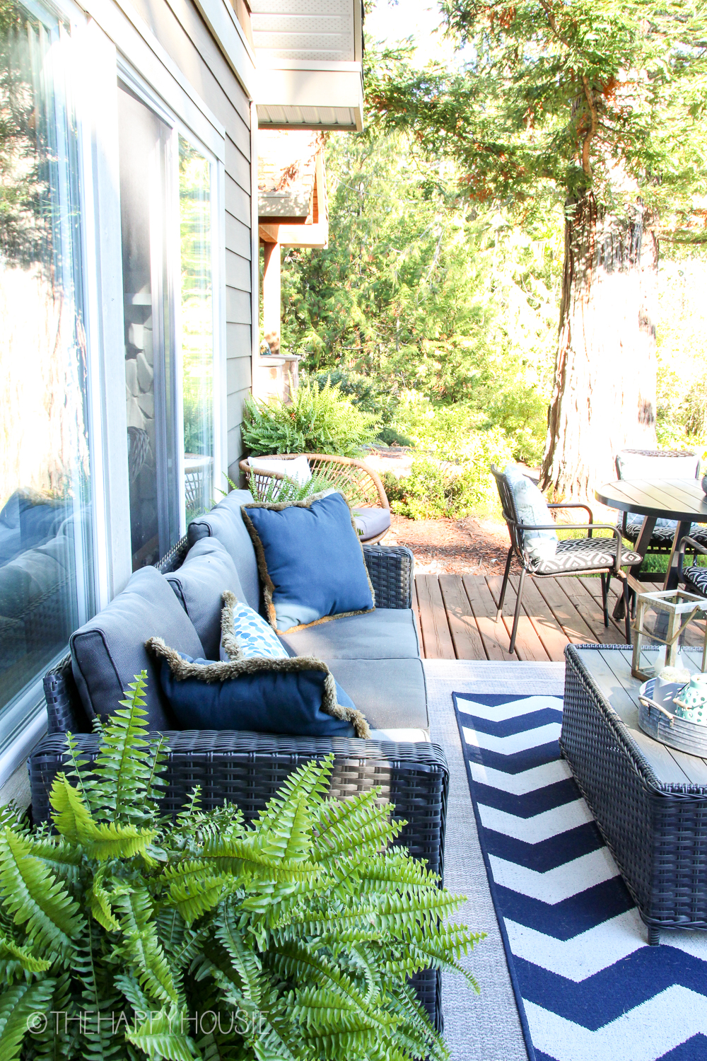 An outdoor sofa, a blue and white rug and an outdoor coffee table on the back deck.