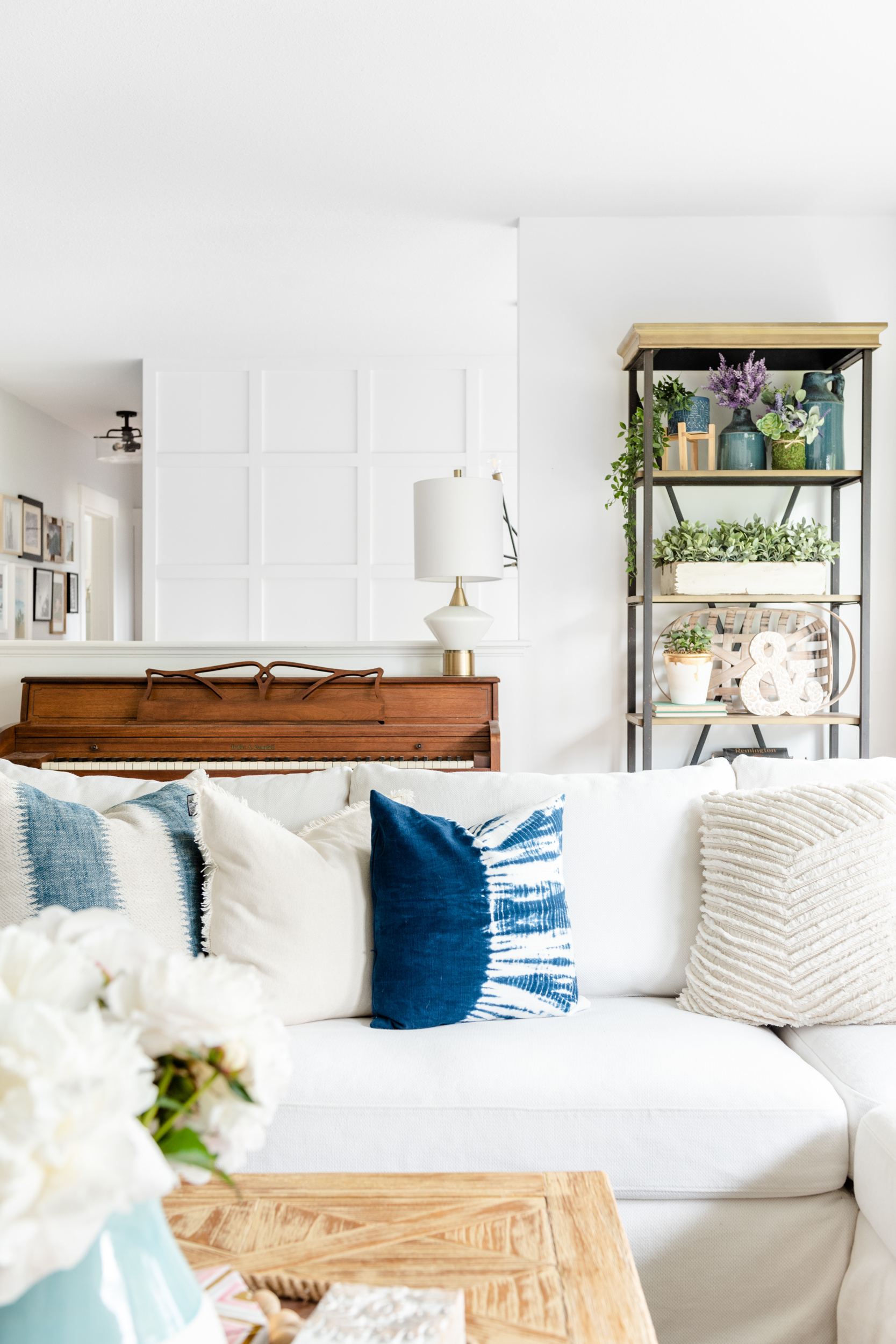 A white and bright living room with a panelled wall in the background and an Ikea Farlov sofa with blue and white pillows