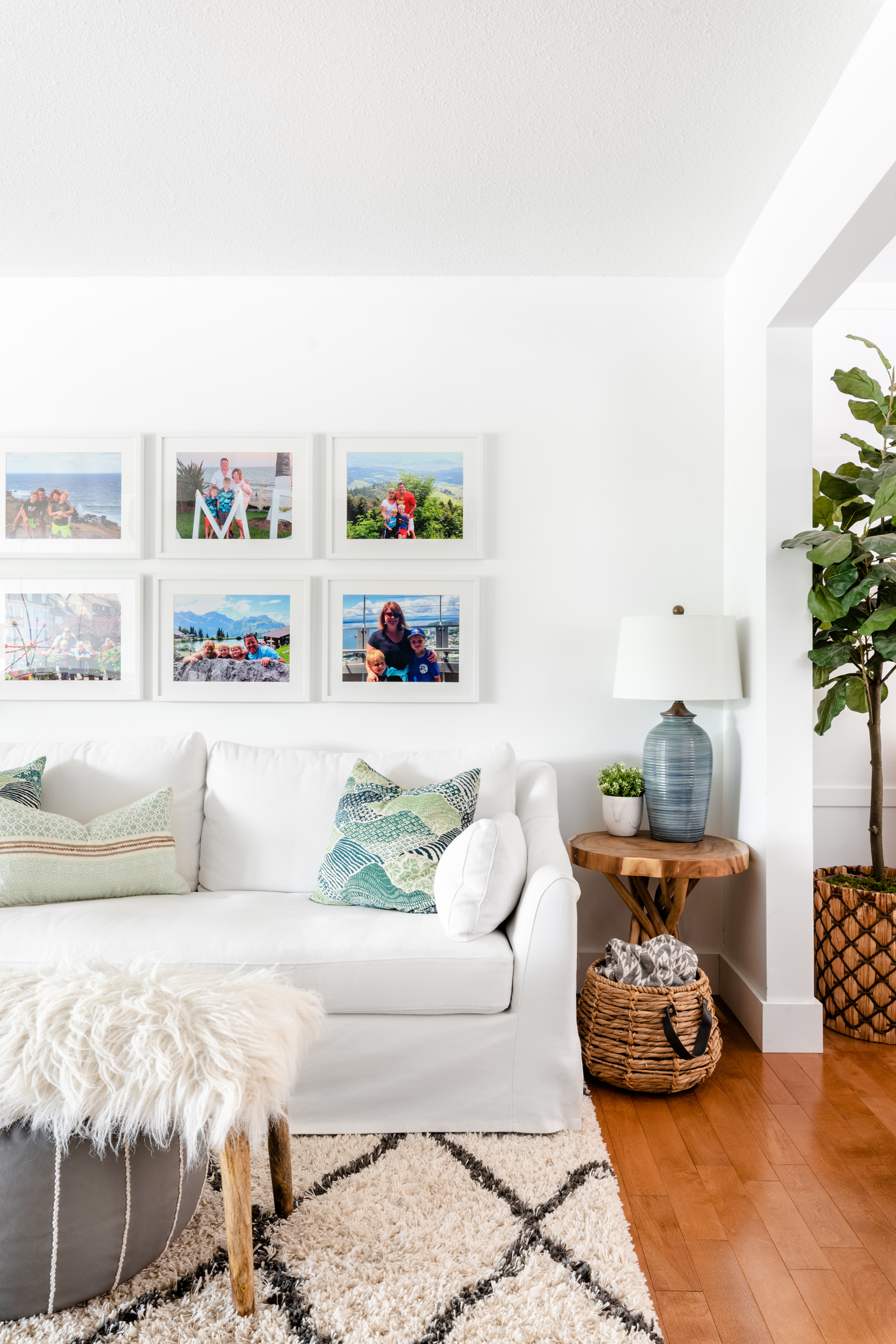 A corner of a family room with white walls, framed family photographs, and an Ikea Farlov white slipcovered sofa