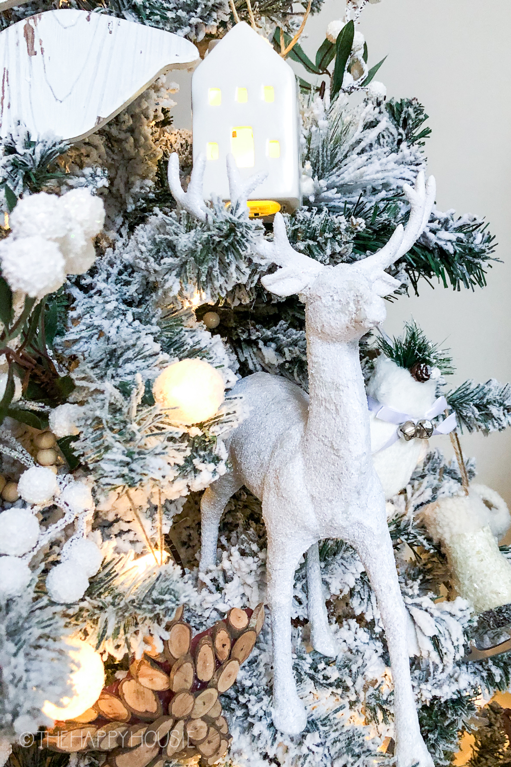 A white sparkly deer is set onto the branches of the tree.