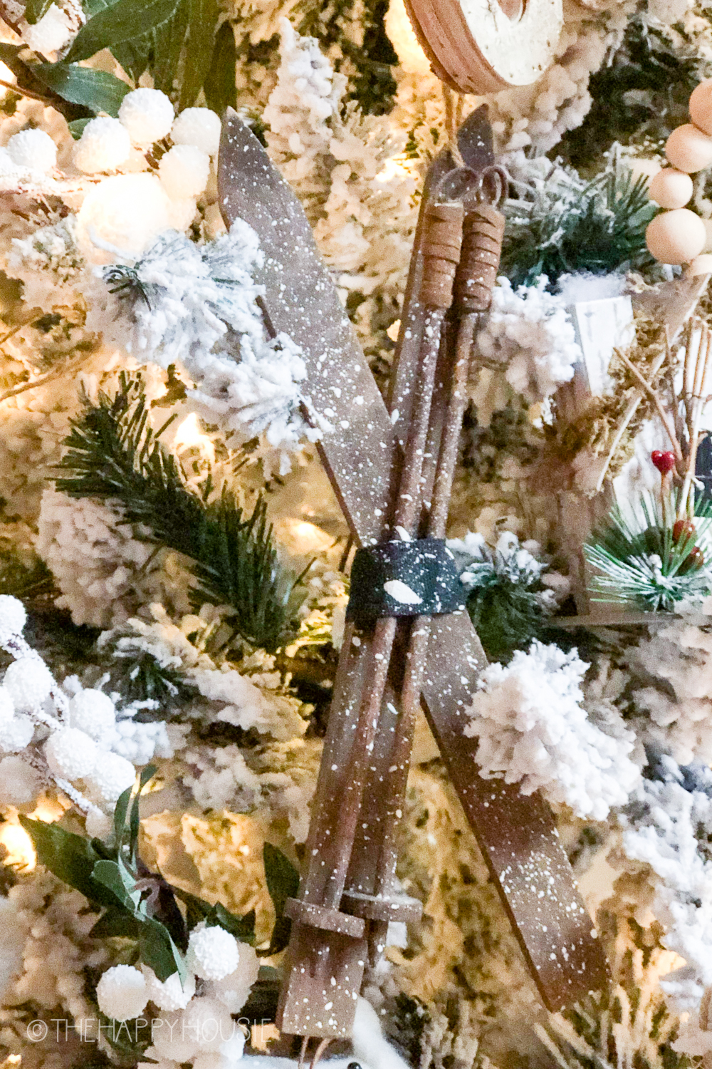 A pair of small wooden skis is hanging on the tree.