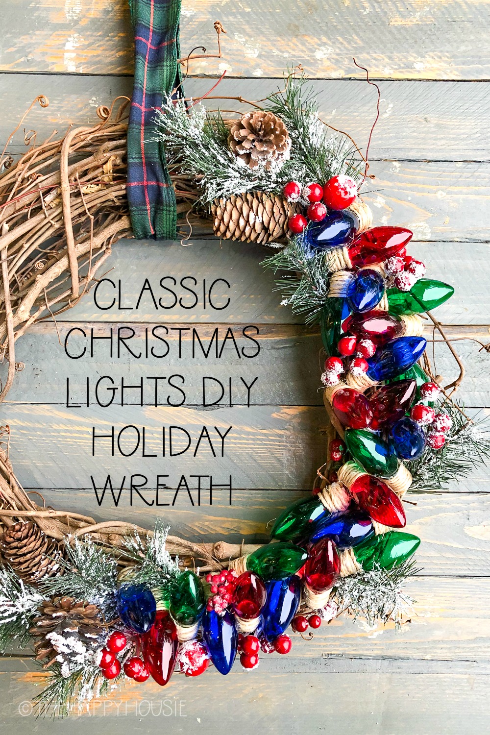 Classic Christmas Lights DIY Holiday Wreath with the wreath hanging on a wooden board.