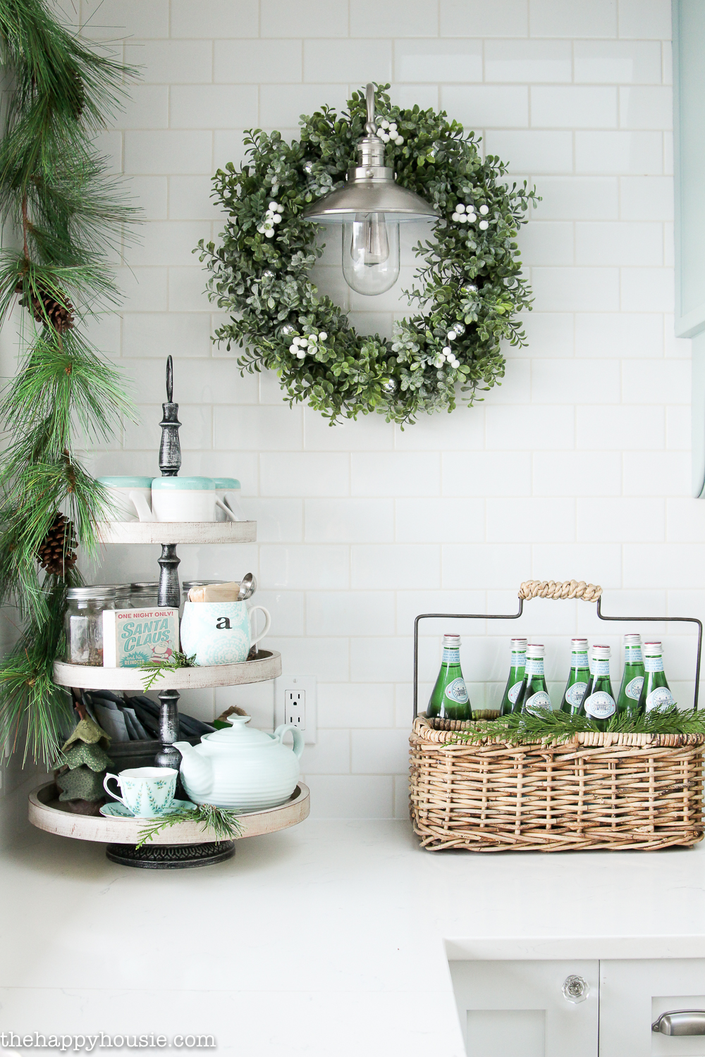 A green and white wreath plus a garland is by the tiered tray.