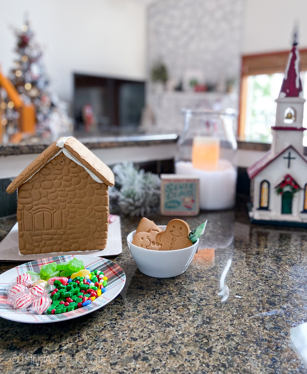 There is a gingerbread house and candy on the counter.