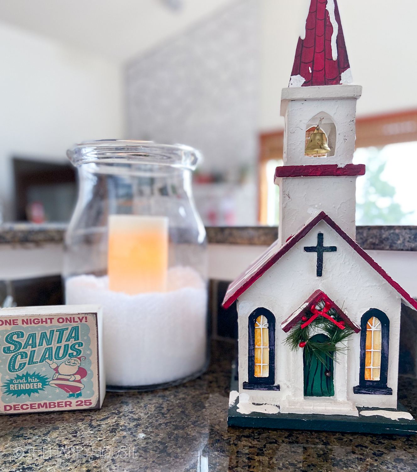 A small church and a candle in a jar on the counter.