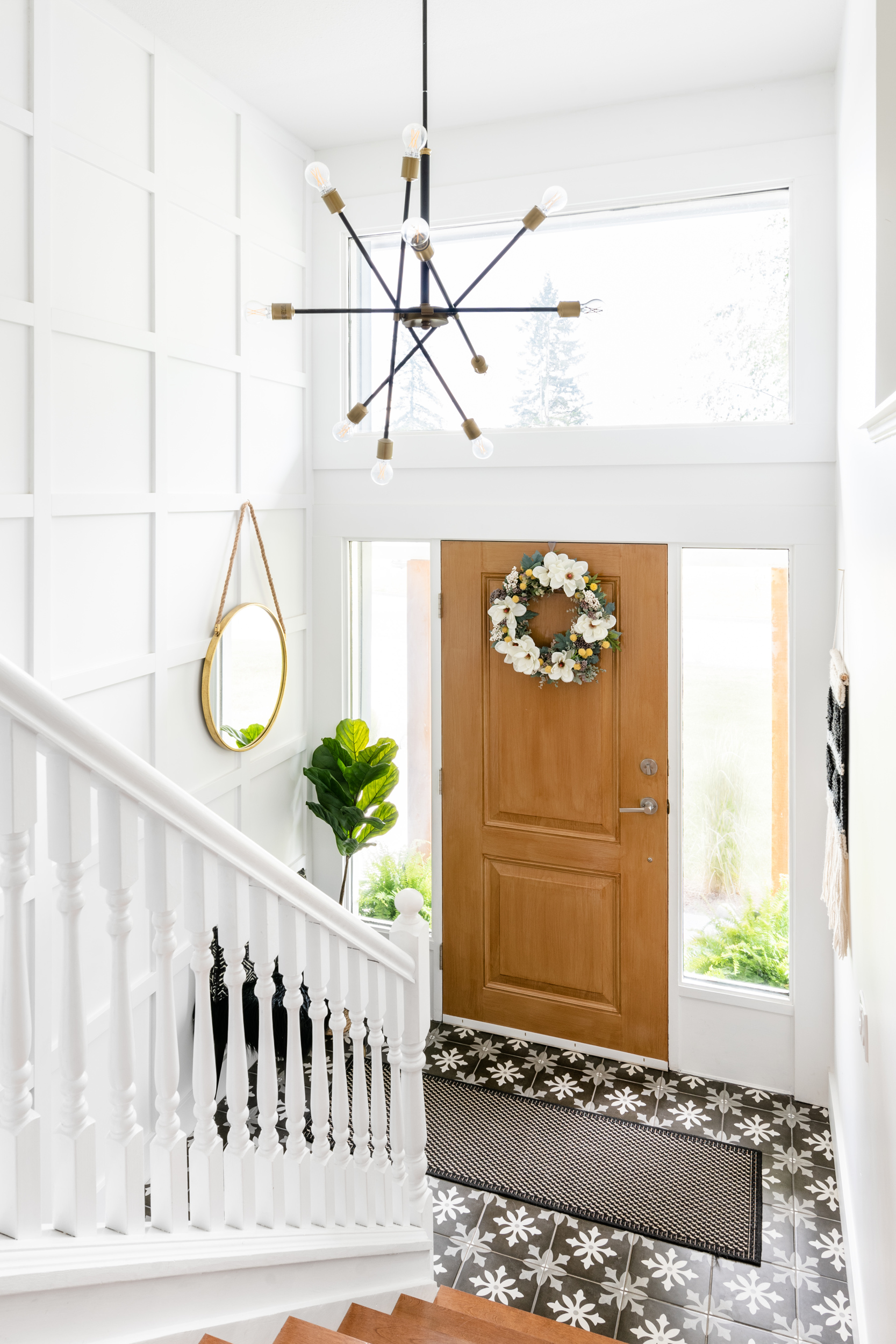 A beautiful split level entry featuring modern lighting, panelled moulding walls, and vintage style tile