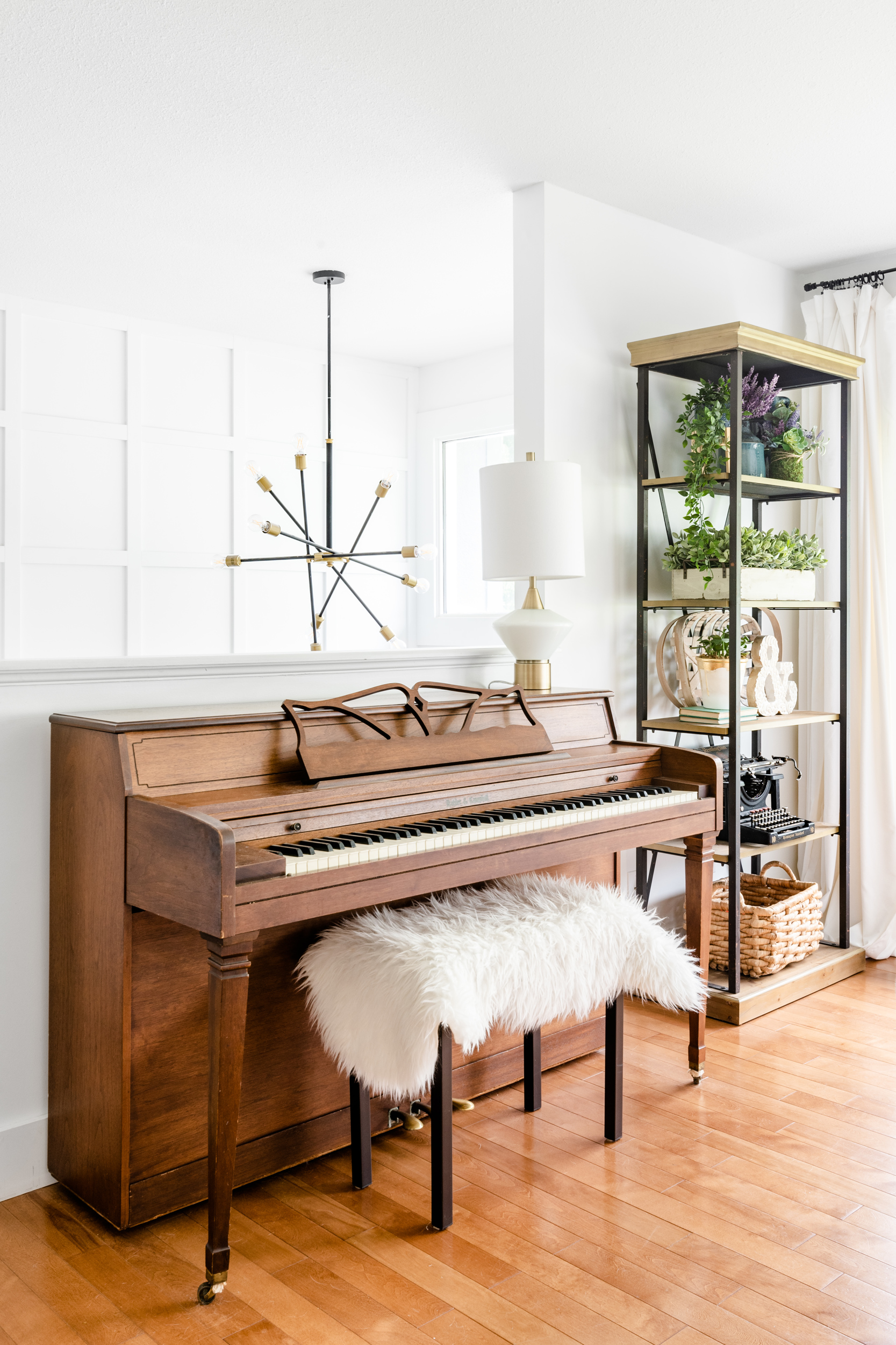 Bright and open living room with a piano and etagere bookcase.
