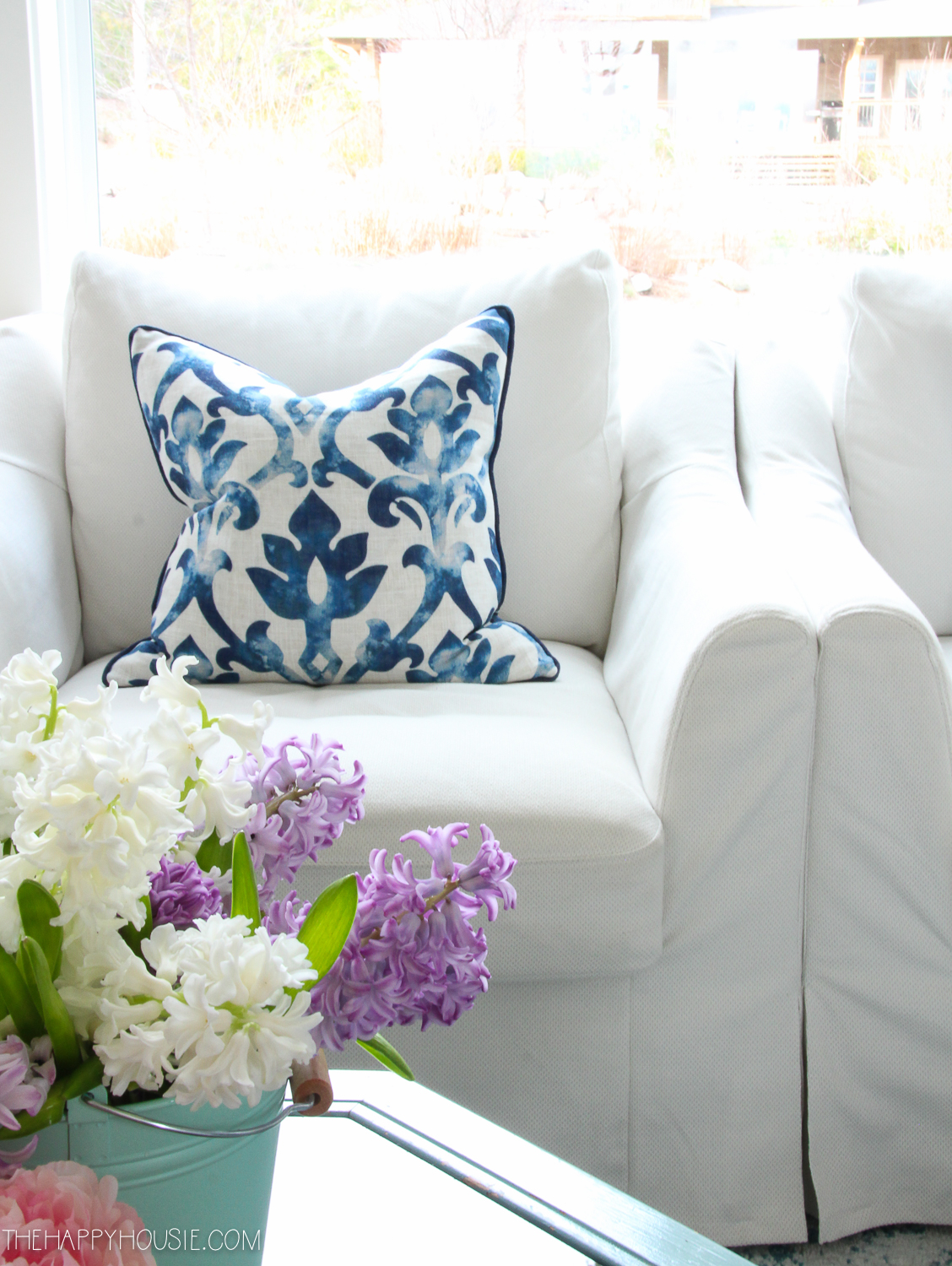 A blue and white throw pillow on a white armchair.