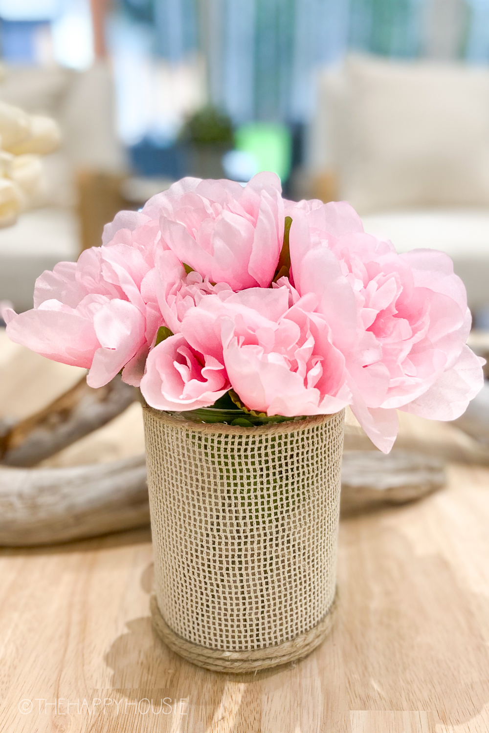 A cane vase with pink peonies in it.