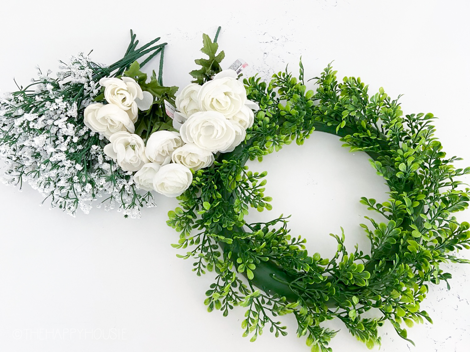 A green wreath and white flowers beside it.