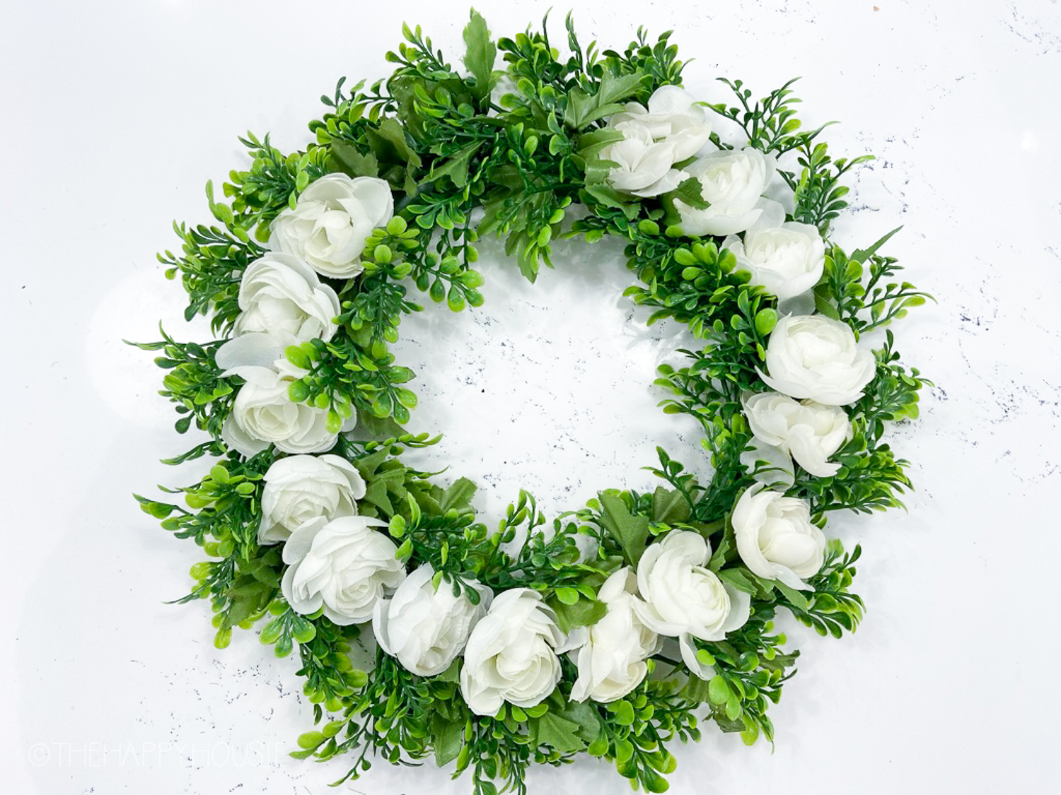 The white flowers all around the green wreath.