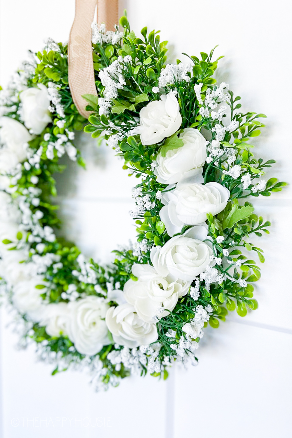 The babys breath, and white roses with the green leaves on the wreath.