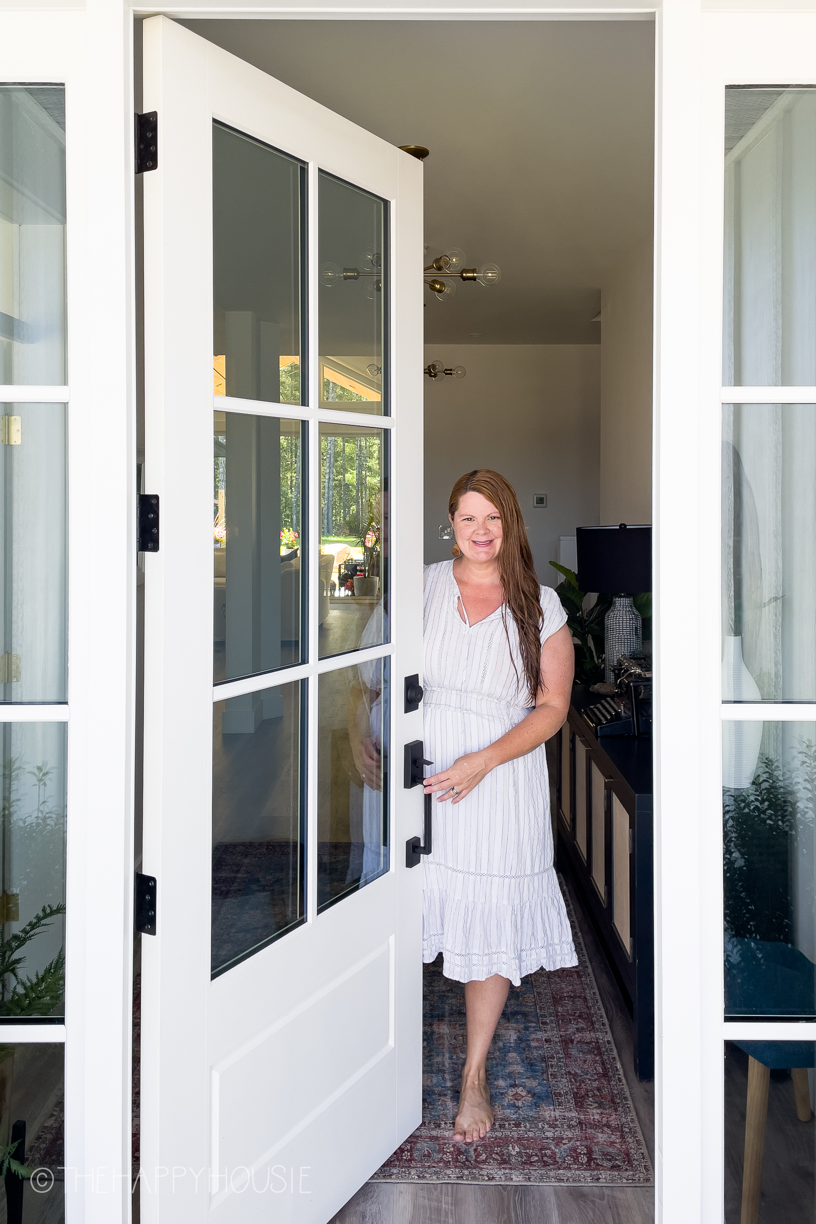 a woman at a traditional front door featuring modern matte black Schlage exterior front handleset 
