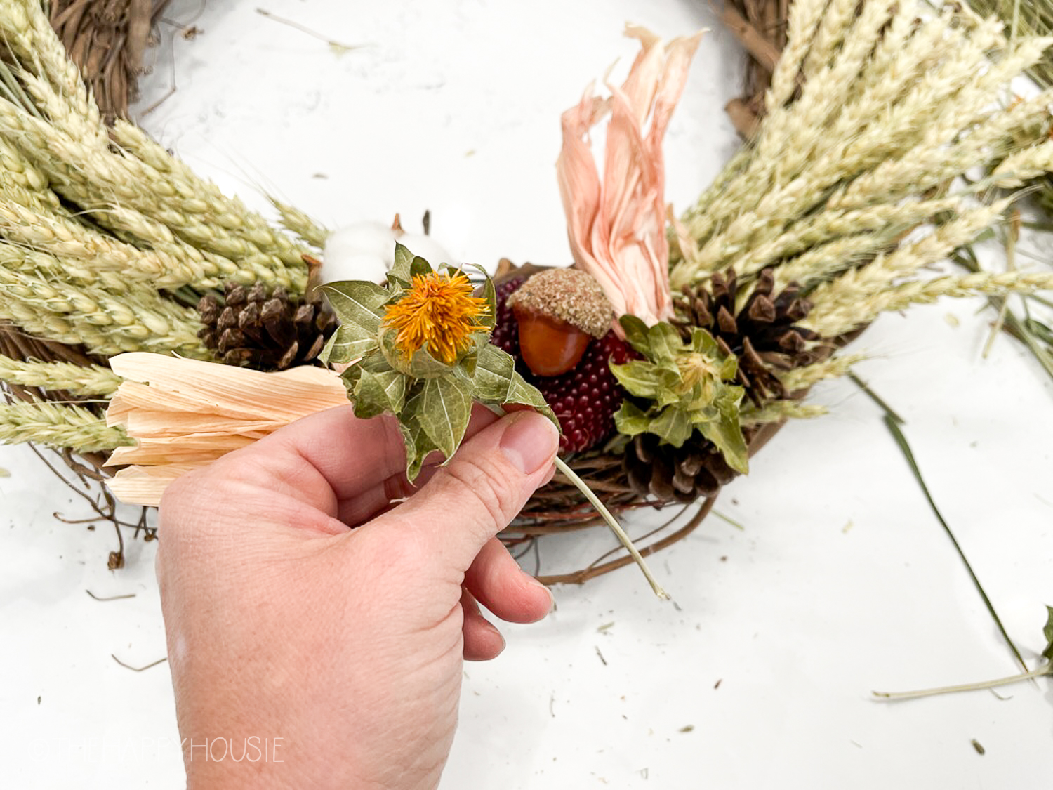 Putting a little dried yellow flower onto the wreath.