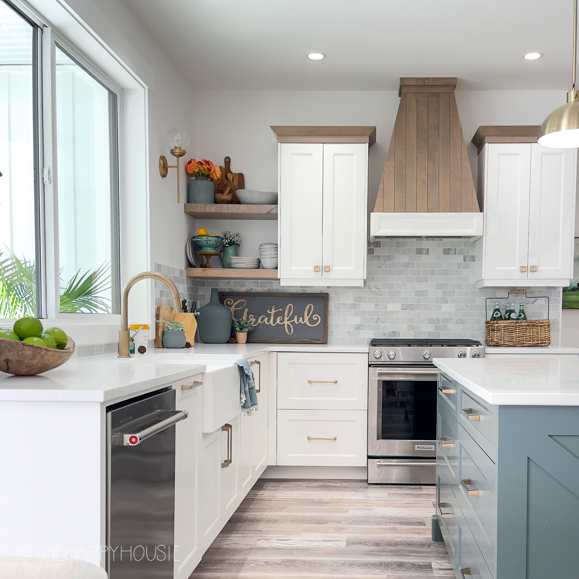 Three tone modern farmhouse style kitchen with a wood hood and wood open shelving