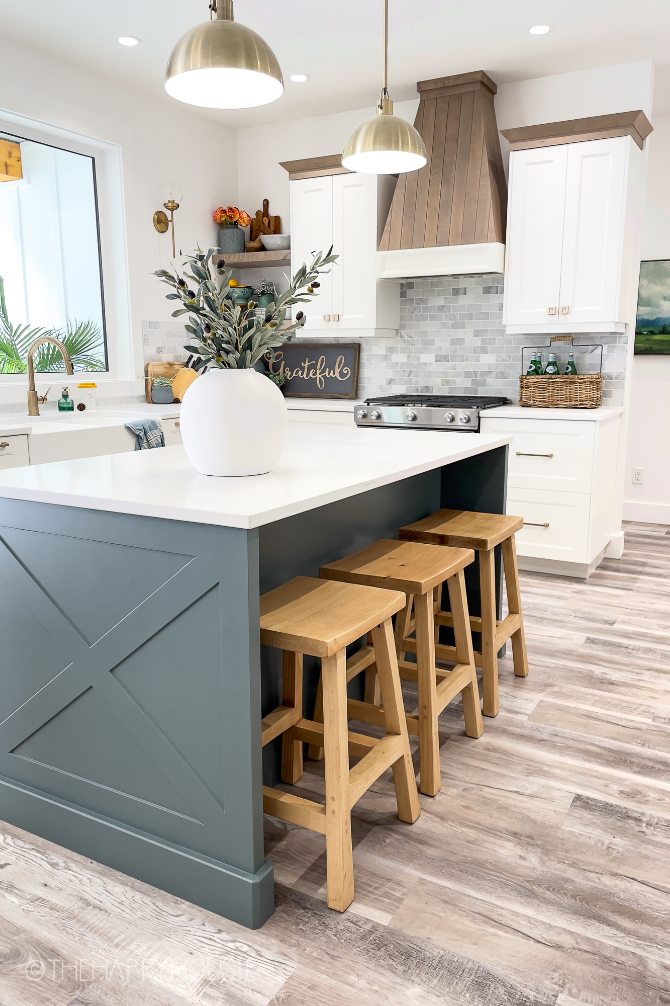 a modern farmhouse kitchen with three tones of white and coloured cabinetry as well as wood cabinet accents
