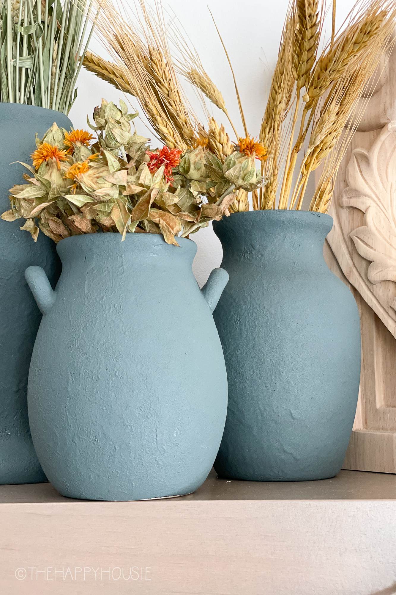 Blue/grey vases with wheat grass and dried flowers.