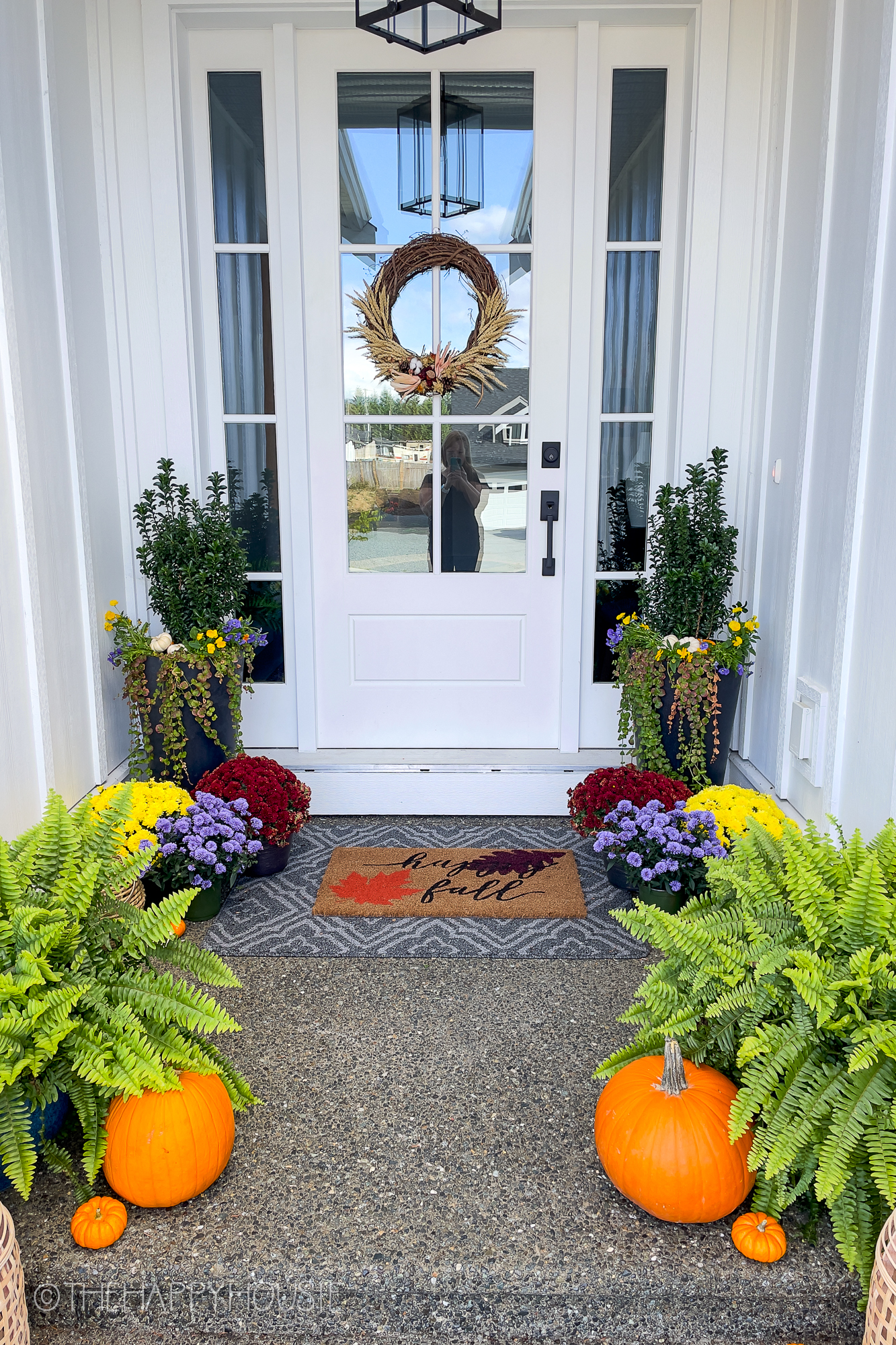 A wooden white door with glass, there is pumpkins on the front porch.