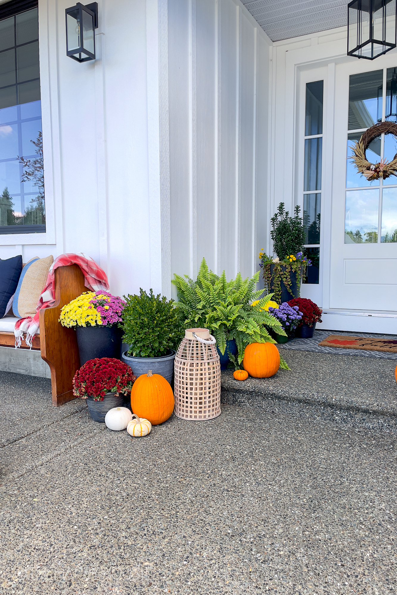 There are pumpkins and containers with flowers on the porch.
