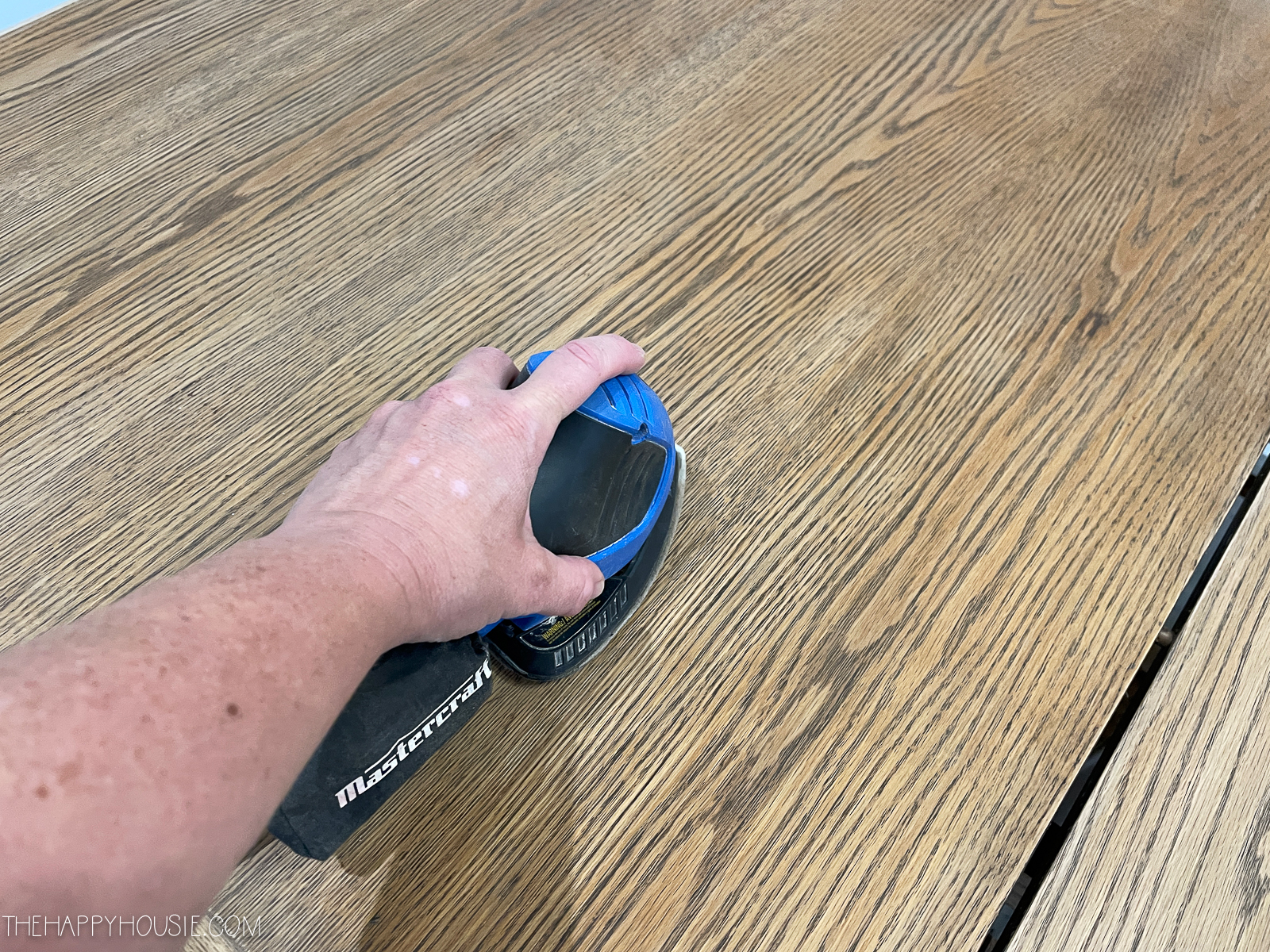 Using a palm sander on the table.