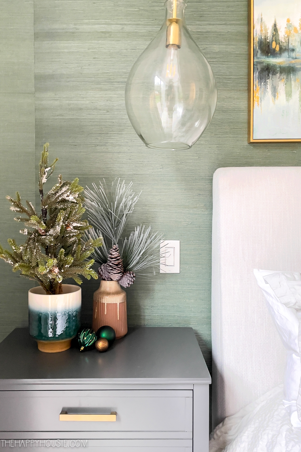 Small branches of evergreen are in vases beside the bed.